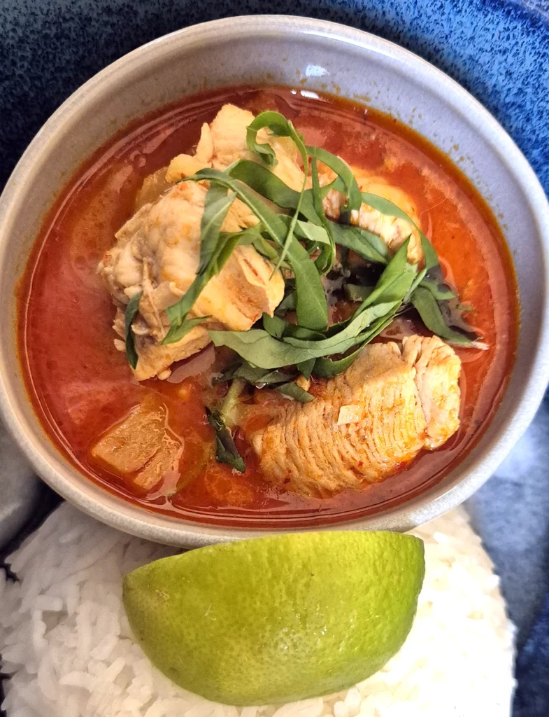 Thai Red Curry with Chicken and Pineapple, served with steamed jasmine rice and a wedge of lime.
